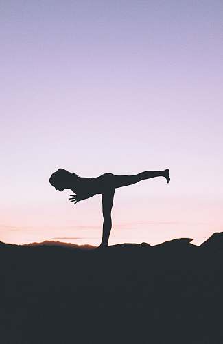 working out silhouette photography of woman standing on right foot yoga